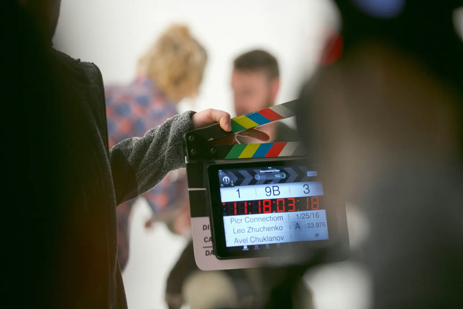 Claqueta de cine marcando el inicio de una grabación, con el equipo trabajando de fondo